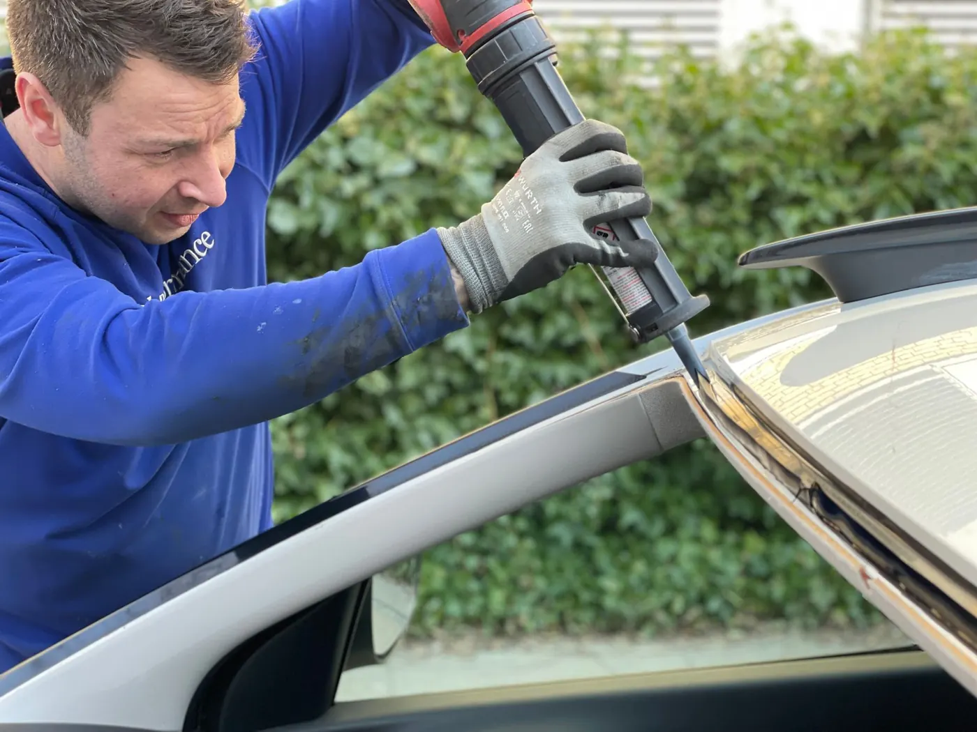 Technician applying windscreen adhesive during replacement